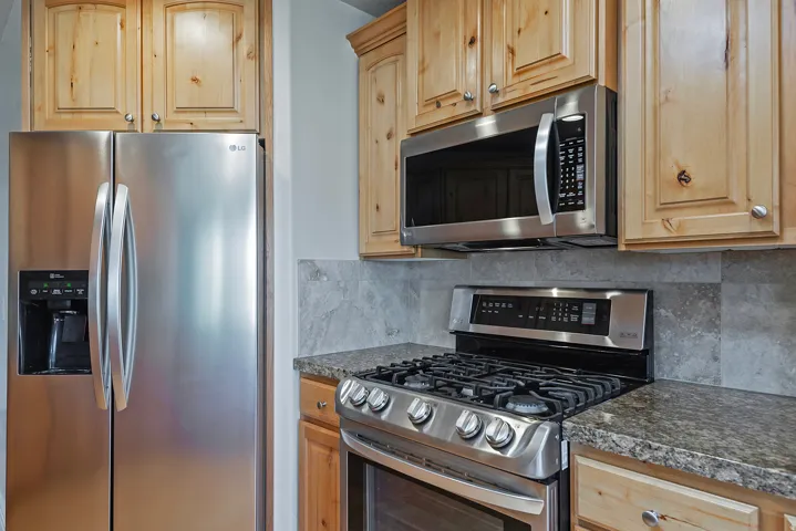 Kitchen featuring stainless steel appliances including a side-by-side refrigerator, gas range, and built-in microwave