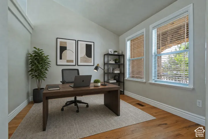 Dedicated office space featuring vaulted ceilings, wood-finish flooring, and white trim