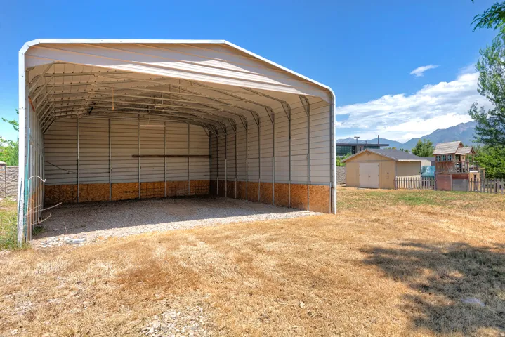 Expansive metal carport featuring a gravel floor and durable corrugated metal siding
