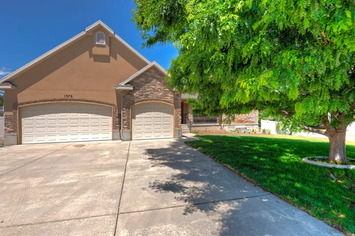 Stucco and stone facade with a two-car garage and additional single-car garage