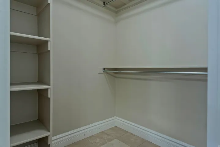 Walk-in closet featuring built-in shelving, a garment rod, baseboard molding, and tile flooring