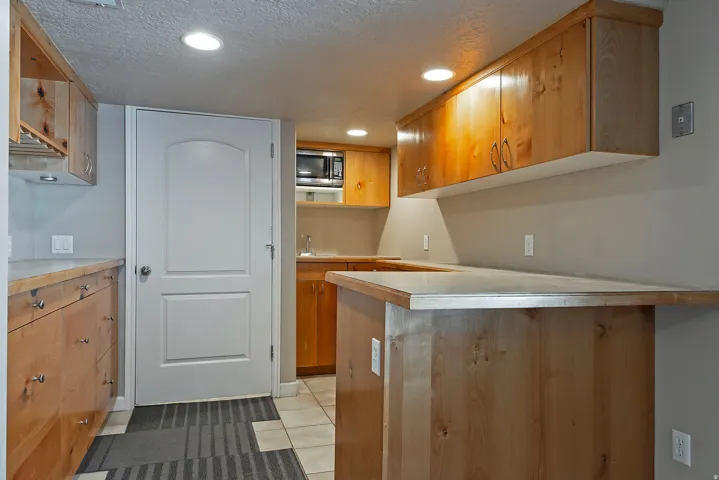 Kitchenette featuring custom wood cabinetry, a built-in microwave, and recessed lighting