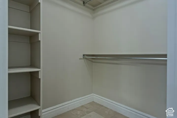Walk-in closet featuring built-in shelving, a garment rod, baseboard molding, and tile flooring