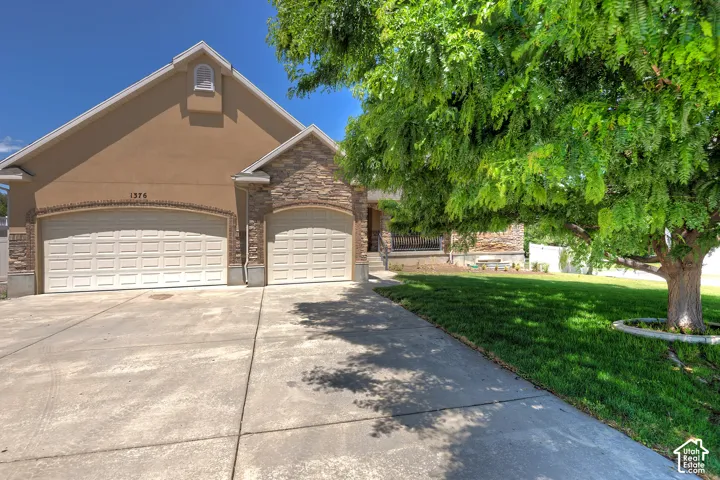 Stucco and stone facade with a two-car garage and additional single-car garage