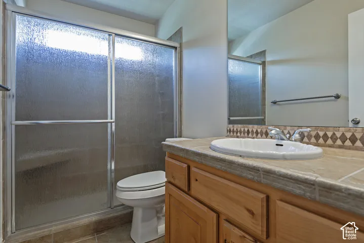 Bathroom featuring a vanity with a drop-in sink, a textured countertop, and a diamond-patterned tile backsplash