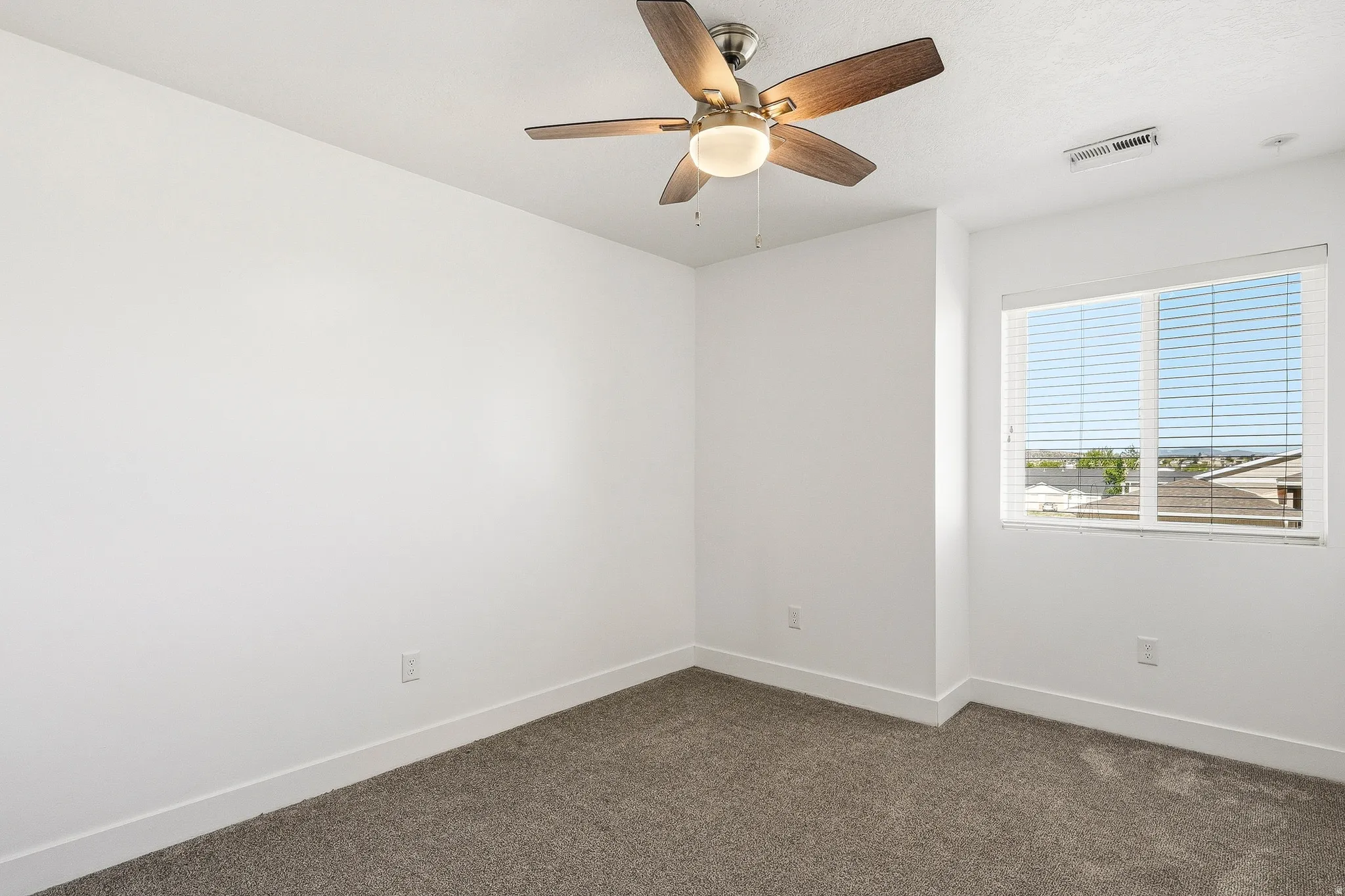 Bedroom featuring carpet flooring, white walls, a ceiling fan with light fixture, white window blinds, and a window providing natural illumination