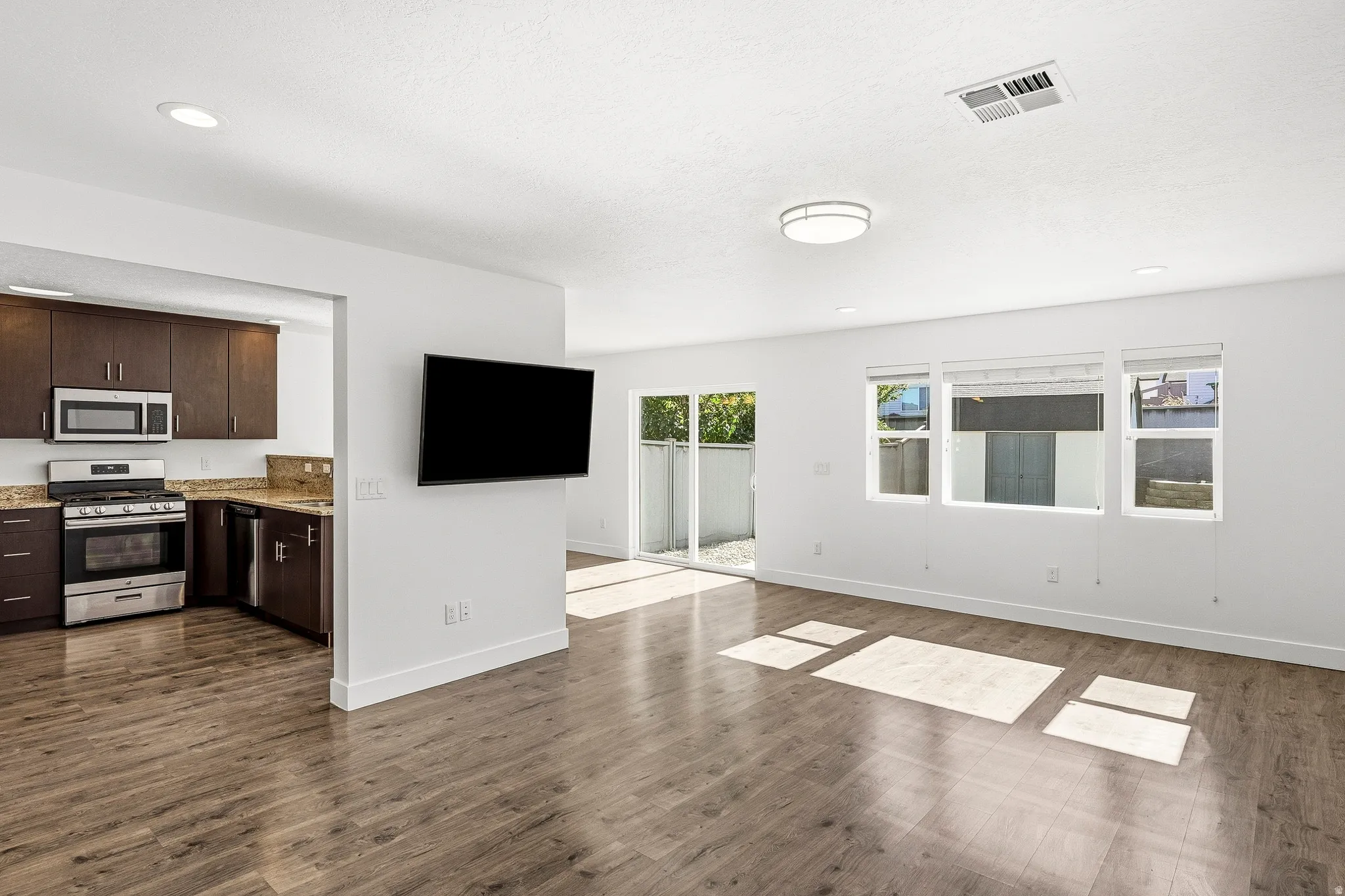 Open-concept living area featuring wood-finish flooring, recessed lighting, and a sliding glass door