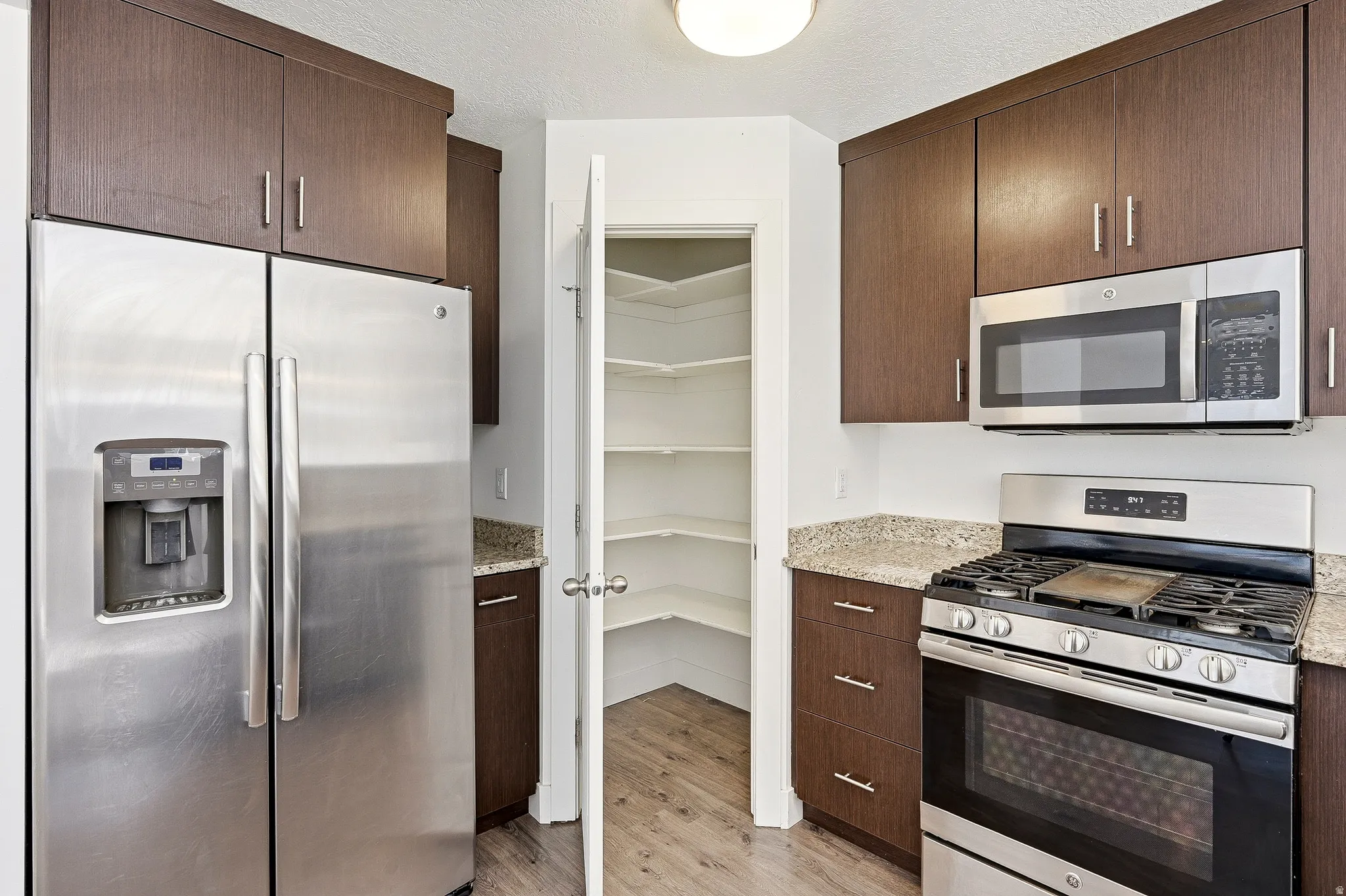 Kitchen featuring rich wood-finish cabinetry, stainless steel appliances, and granite countertops