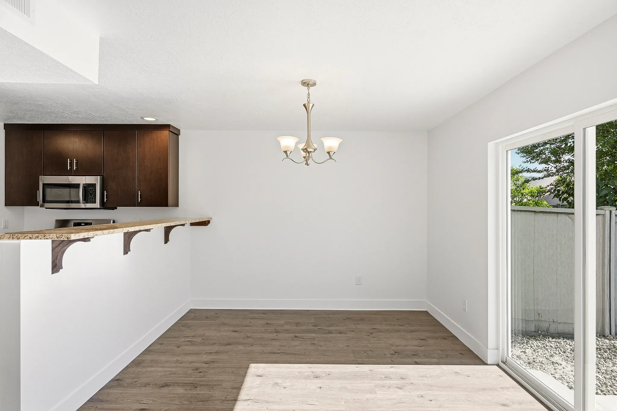 Dining area featuring wood-finish flooring, a contemporary chandelier, and a sliding glass door