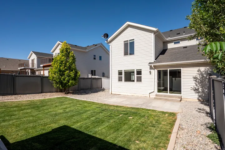 Rear exterior featuring light-colored siding, a concrete patio, and a sliding glass door