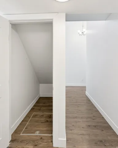 Spacious hallway featuring wood-finish flooring, white walls, and a recessed ceiling light