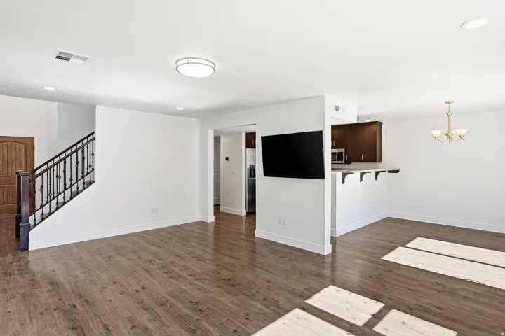 Open-concept living area with wood-finish flooring, a contemporary ceiling light fixture, and recessed lighting