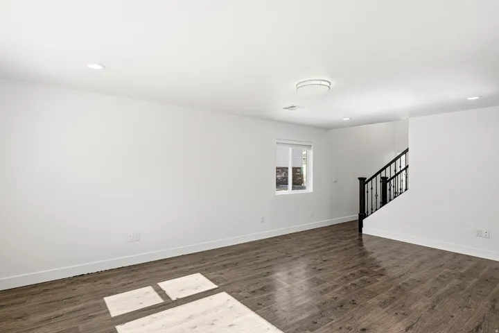 Spacious room featuring wood-finish flooring, recessed lighting, and a contemporary flush-mount ceiling fixture