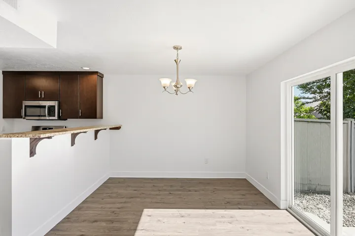 Dining area featuring wood-finish flooring, a contemporary chandelier, and a sliding glass door