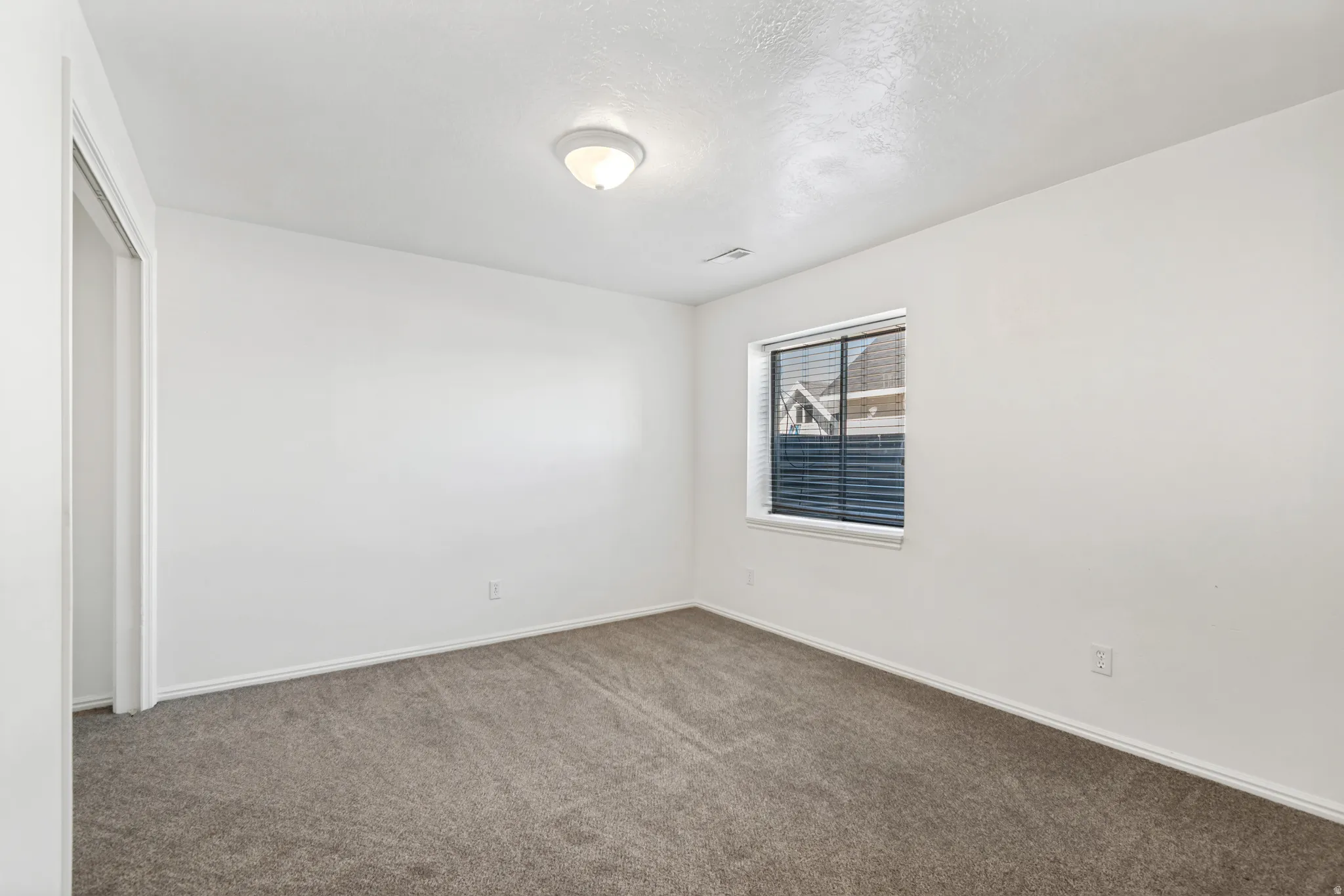 Neutral wall finishes, recessed window with horizontal blinds, flush mount ceiling light fixture, baseboard trim, and wall-to-wall carpeting