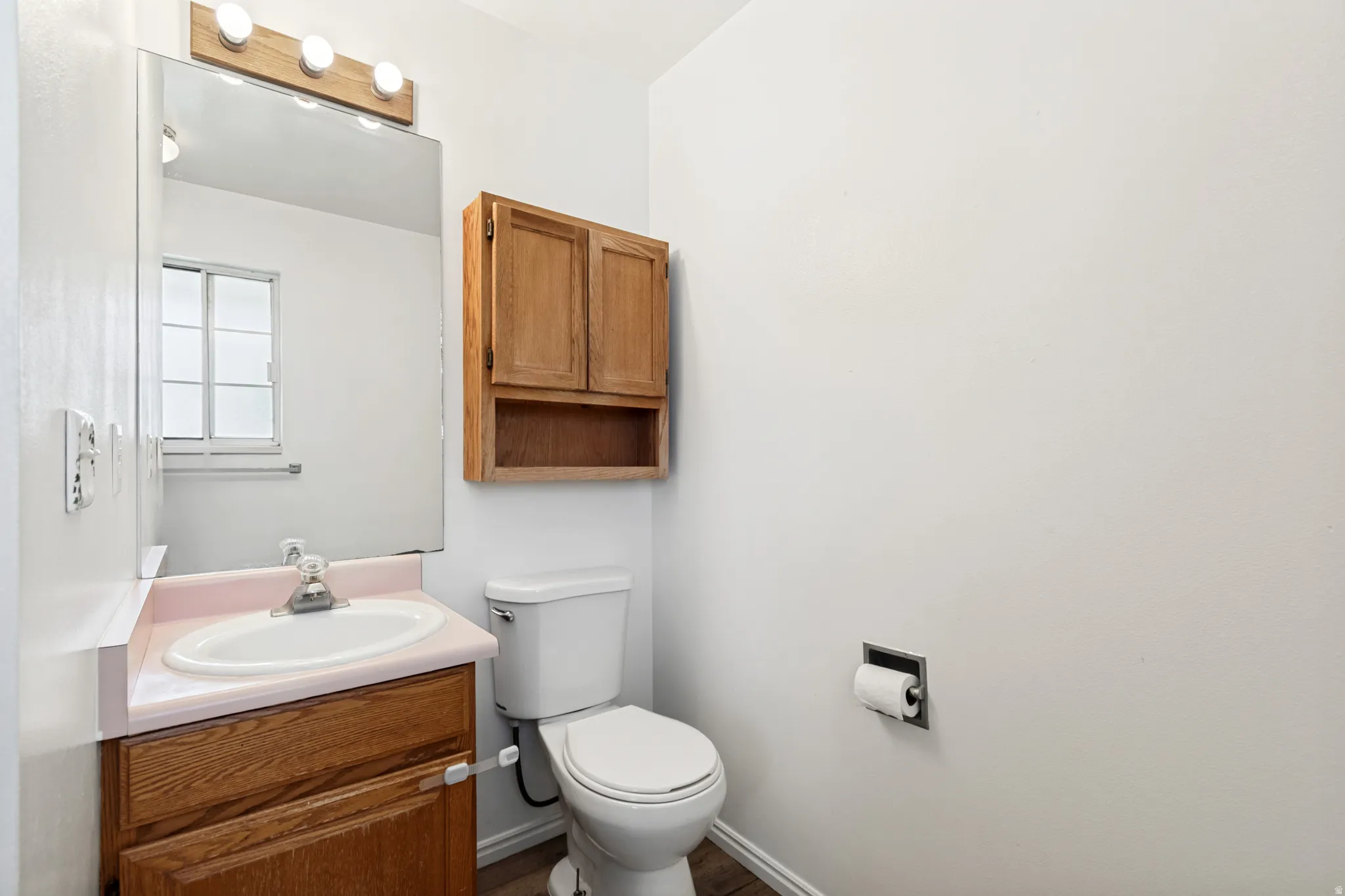Bathroom vanity with a pink countertop, white sink, and chrome faucet