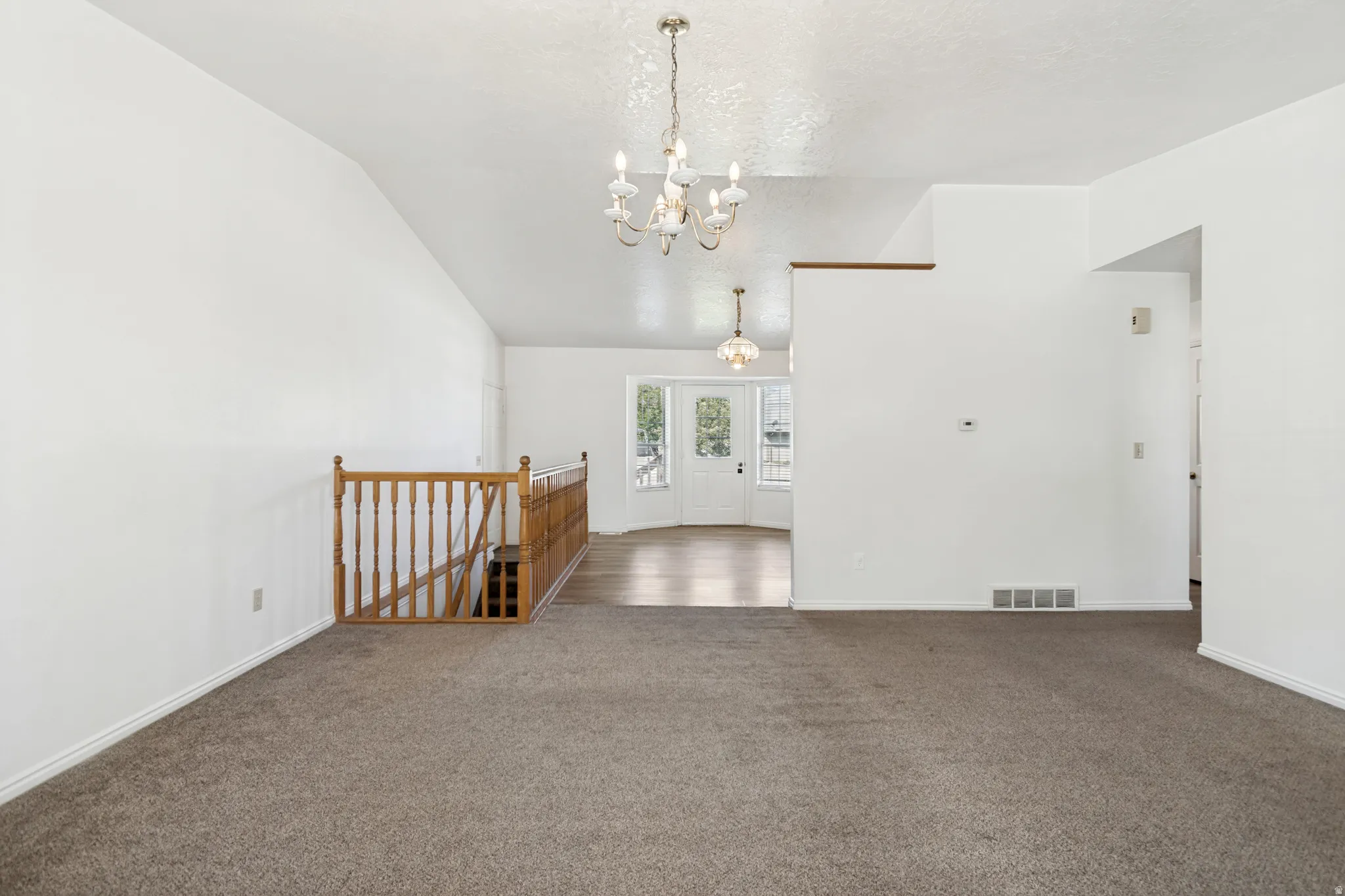 Spacious interior featuring vaulted ceilings and neutral-toned carpeting