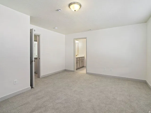Spacious room featuring light gray carpeting, crisp white walls, and a semi-flush mount ceiling fixture