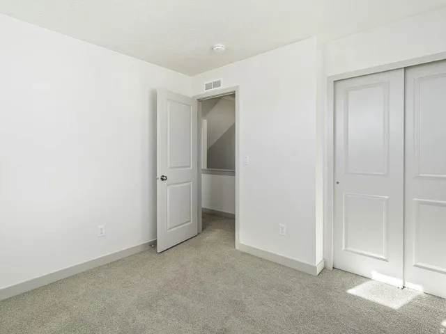 Carpeted room featuring white walls, a white paneled door, and a two-door sliding closet