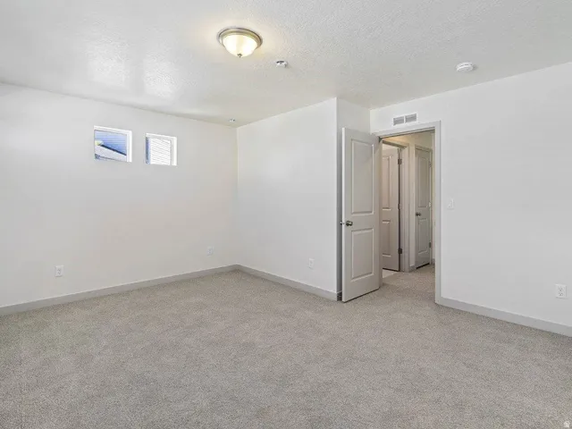 Carpeted room with neutral wall tones and two square windows