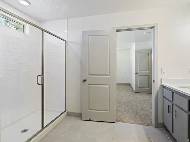 Glass-enclosed shower with subway tile surround and a tiled floor