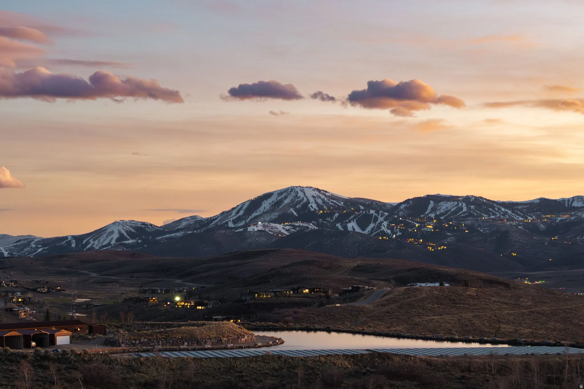 Expansive mountainous landscape featuring snow-capped peaks and scattered residential structures