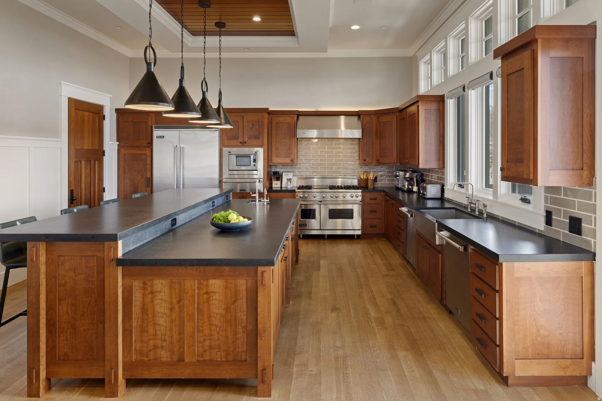 Gourmet kitchen with extensive dark wood cabinetry, a large central island with seating, stainless steel appliances, and wood-finish flooring