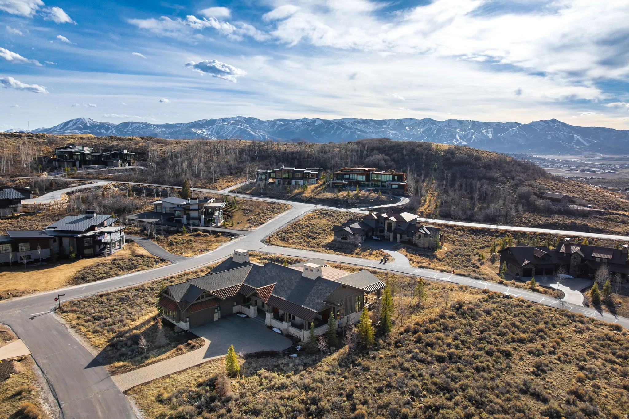 Mountainous terrain with distant snow-capped peaks, featuring multiple contemporary residences