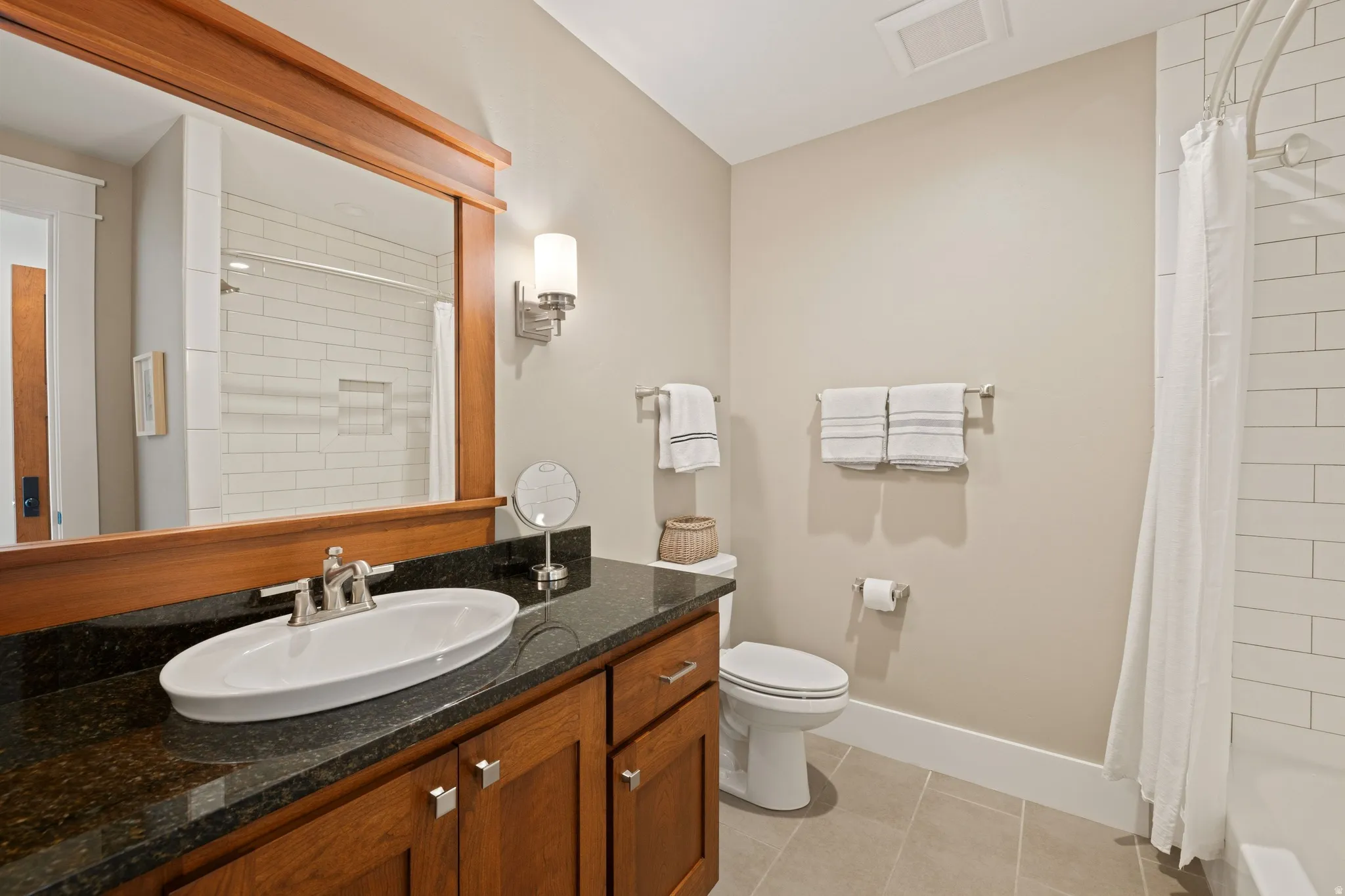 Bathroom featuring a dark wood vanity with a vessel sink, dark stone countertop, and brushed nickel fixtures
