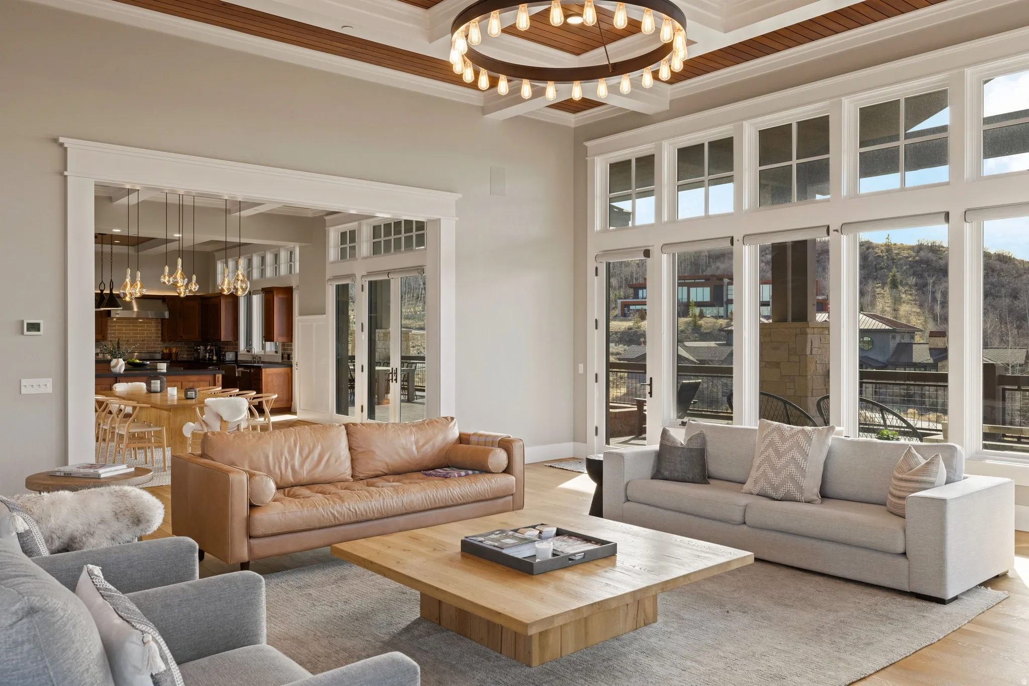 Great room featuring a coffered ceiling, a large circular chandelier, and light wood-finish flooring