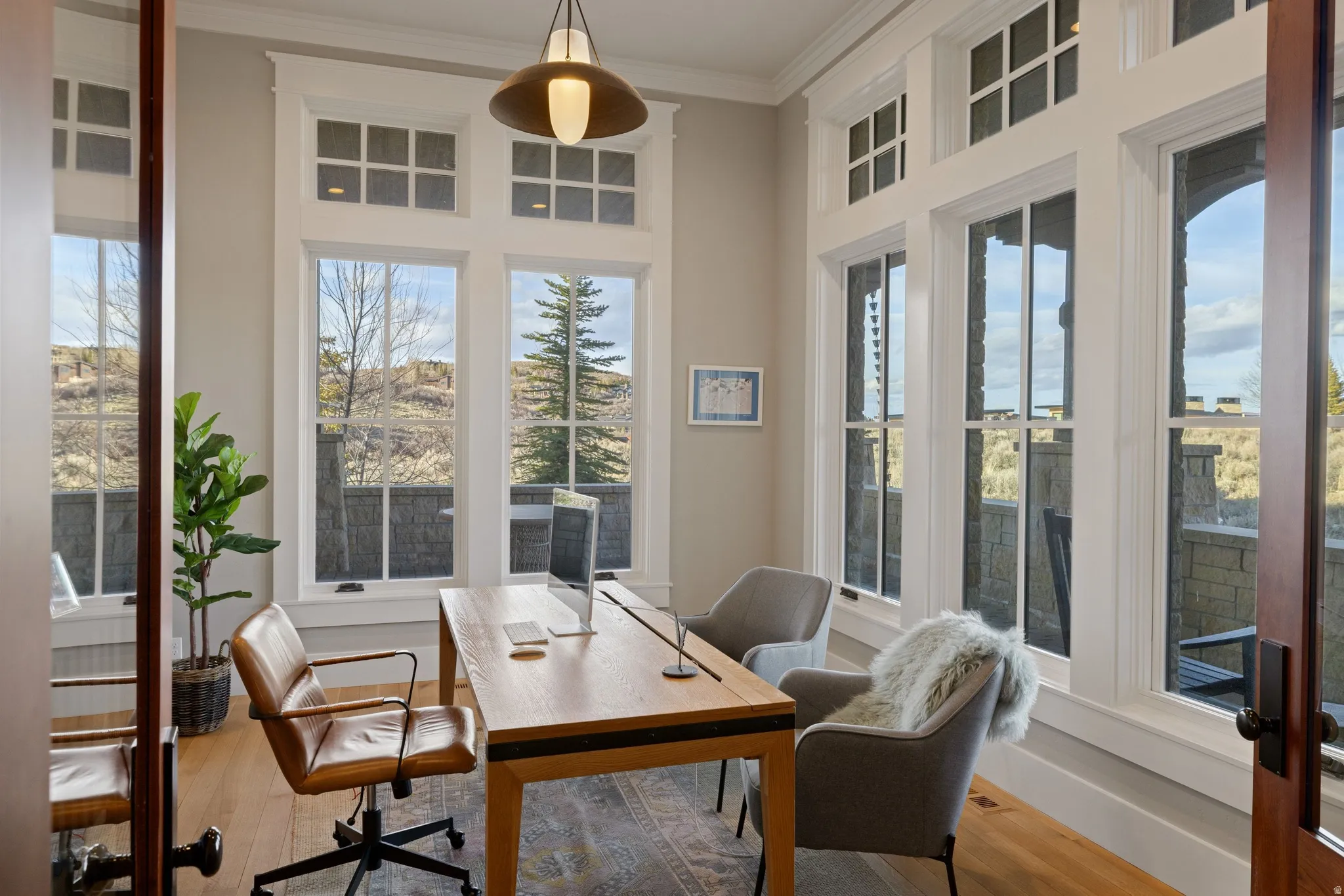 Spacious room featuring multiple large windows with transom details, wood-finish flooring, and a contemporary pendant light fixture