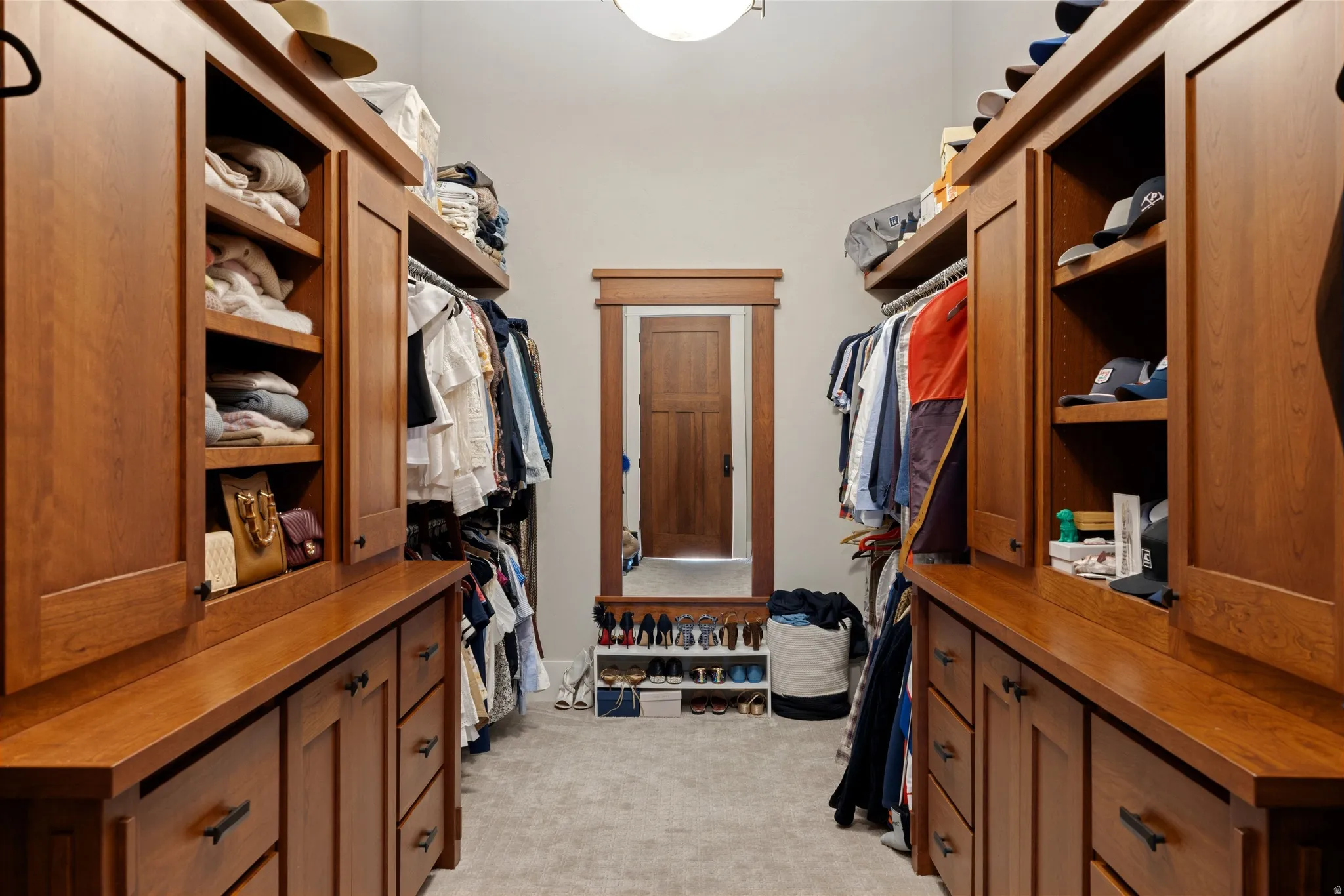 Walk-in closet featuring extensive built-in wooden cabinetry, open shelving, and hanging rods