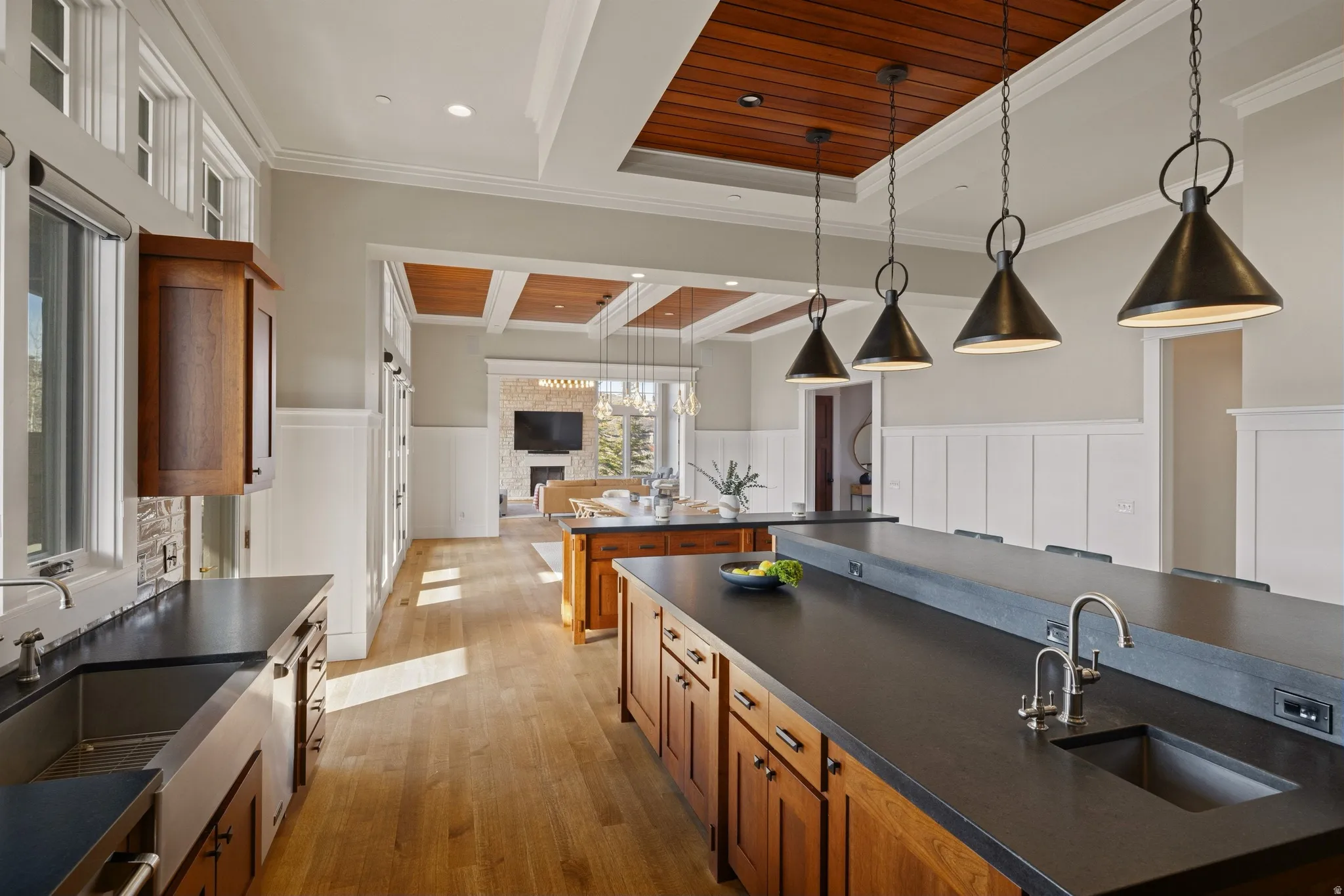 Gourmet kitchen featuring a large island with sink, dark countertops, and wood-finish flooring