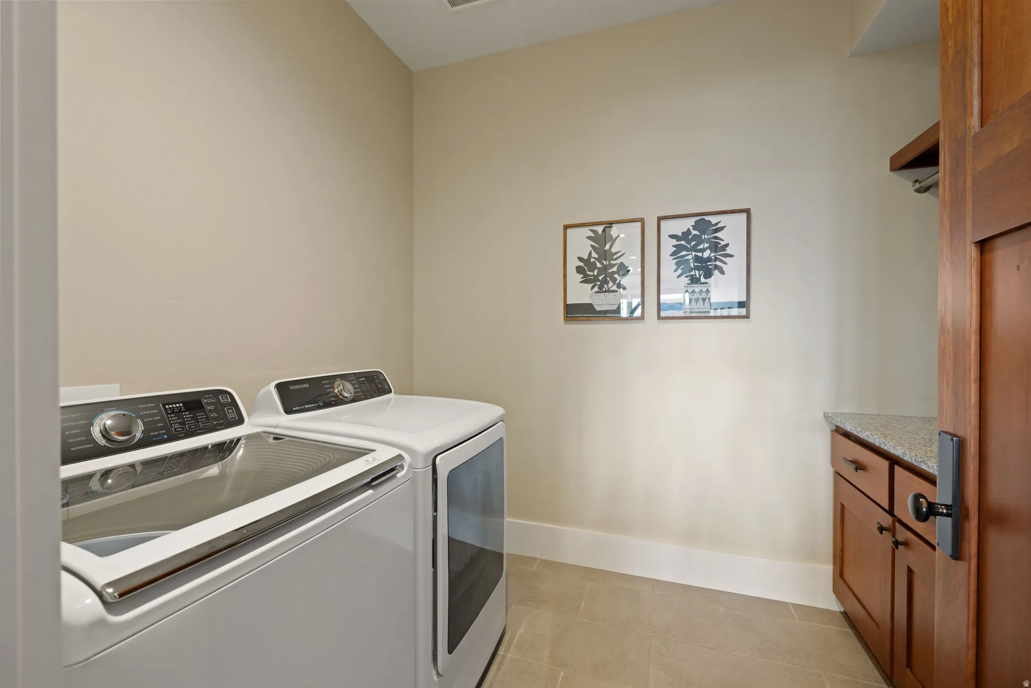 Laundry area featuring tile flooring, built-in cabinetry with a stone-finish countertop, and a wood door frame