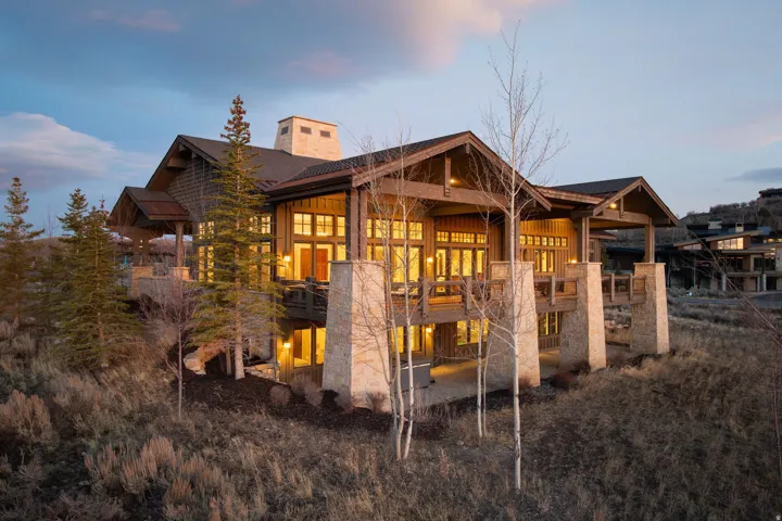 Multi-level home featuring extensive natural wood siding, stone pillar accents, and multiple covered balconies