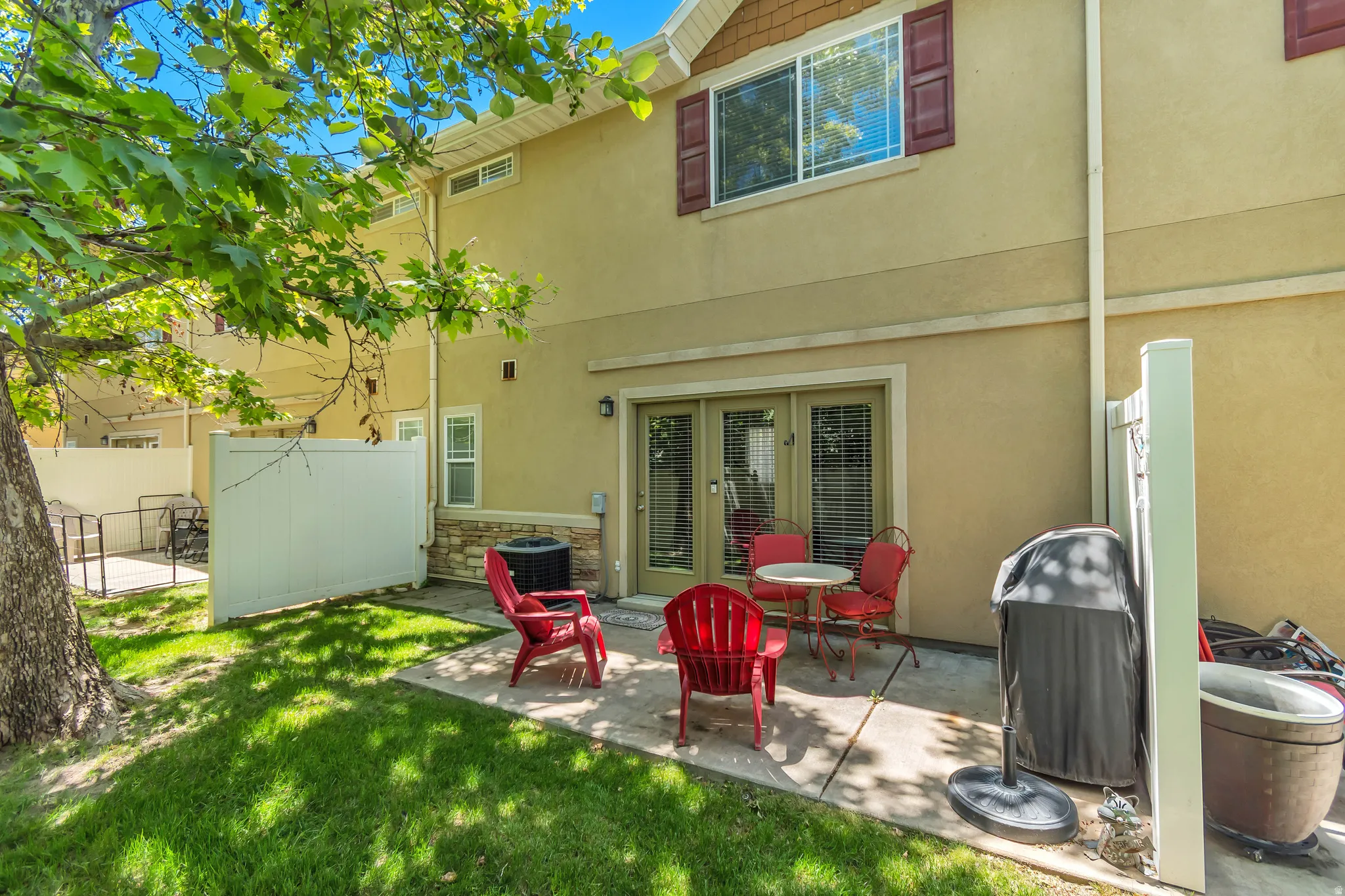 Private patio area with direct access to interior spaces, featuring a stone veneer accent wall and a fully fenced perimeter