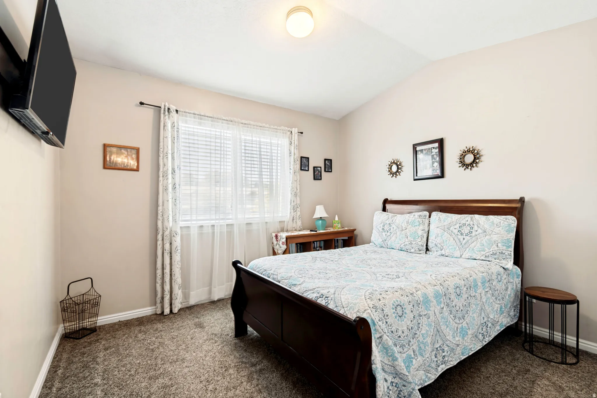 Carpeted room featuring a single window, vaulted ceiling, built-in ceiling light fixture, and neutral wall tones