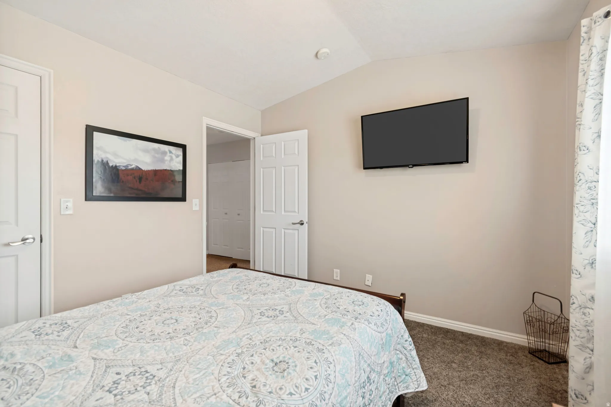 Bedroom featuring vaulted ceilings, neutral wall tones, carpet flooring, and white trim