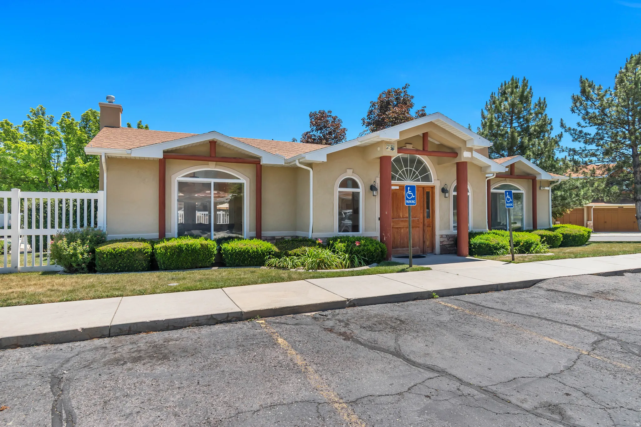 Stucco exterior building featuring a covered entryway with columns, an arched transom window above double wooden doors, and arched windows