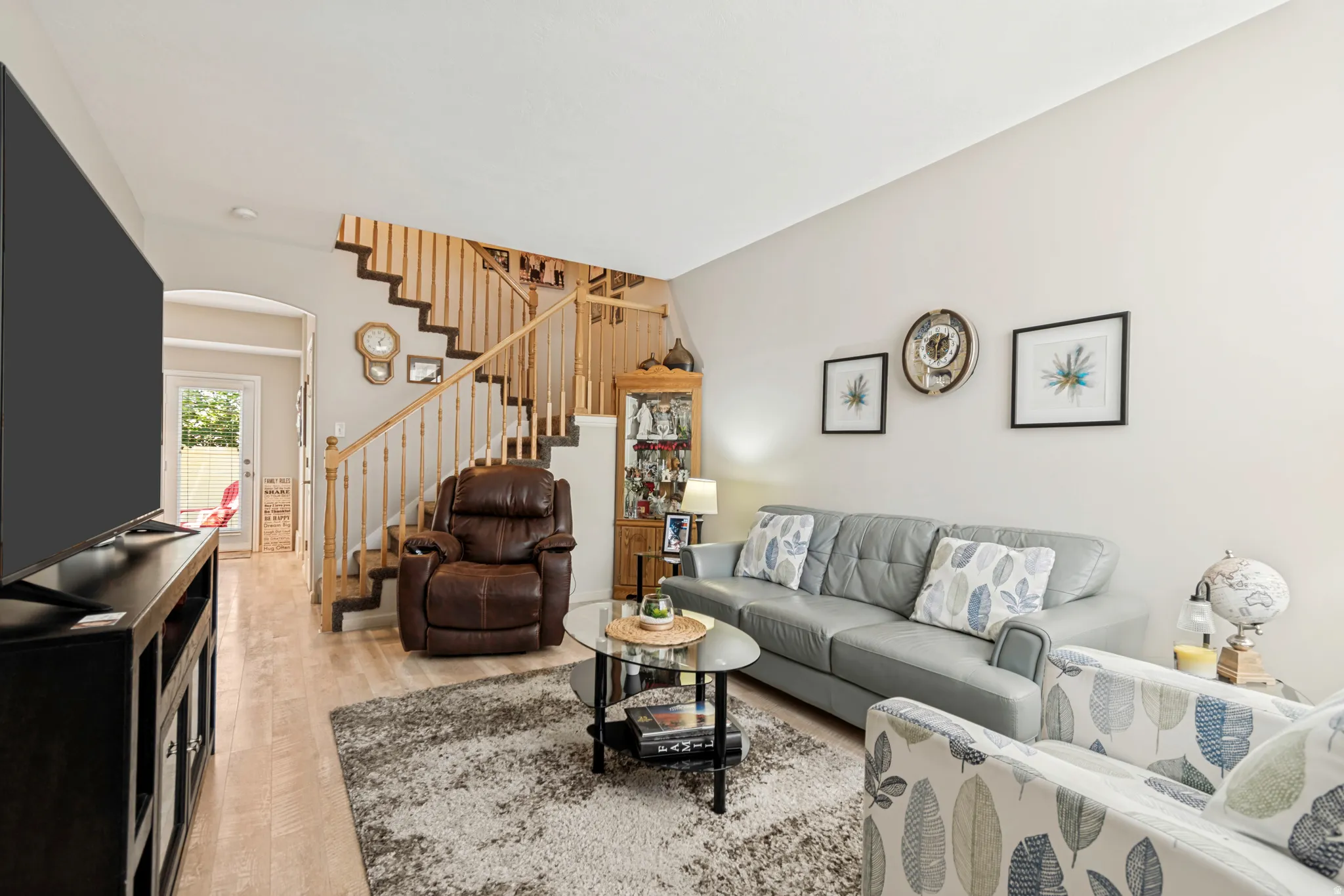 Living space featuring wood-finish flooring, a wood staircase with balusters, and light-toned walls