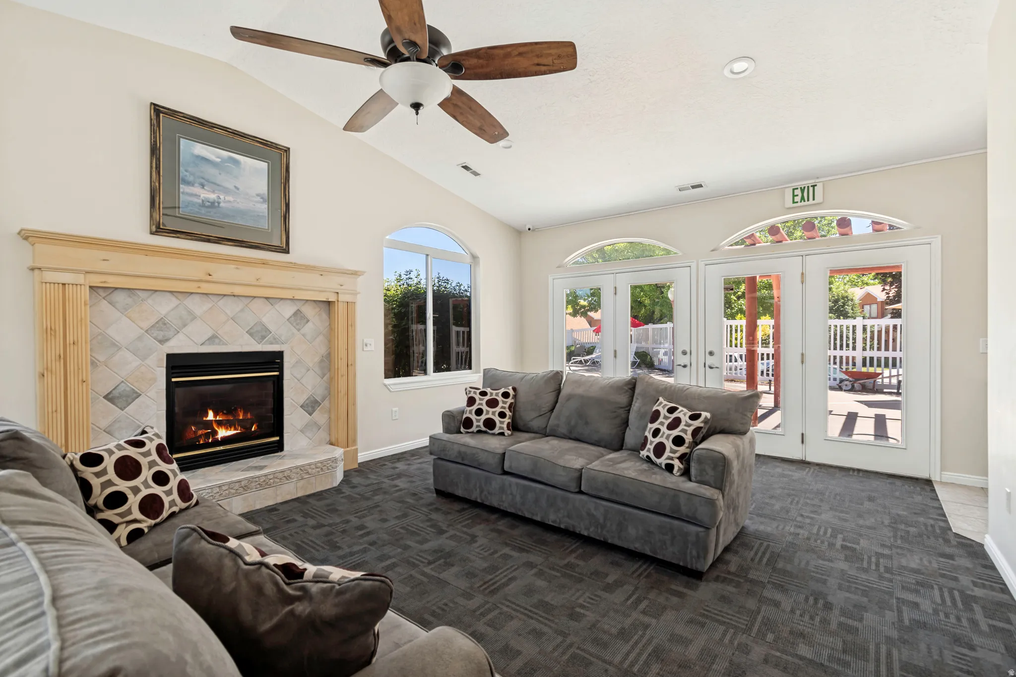 Vaulted ceiling living area featuring a central fireplace with tile surround, wood mantel, and hearth