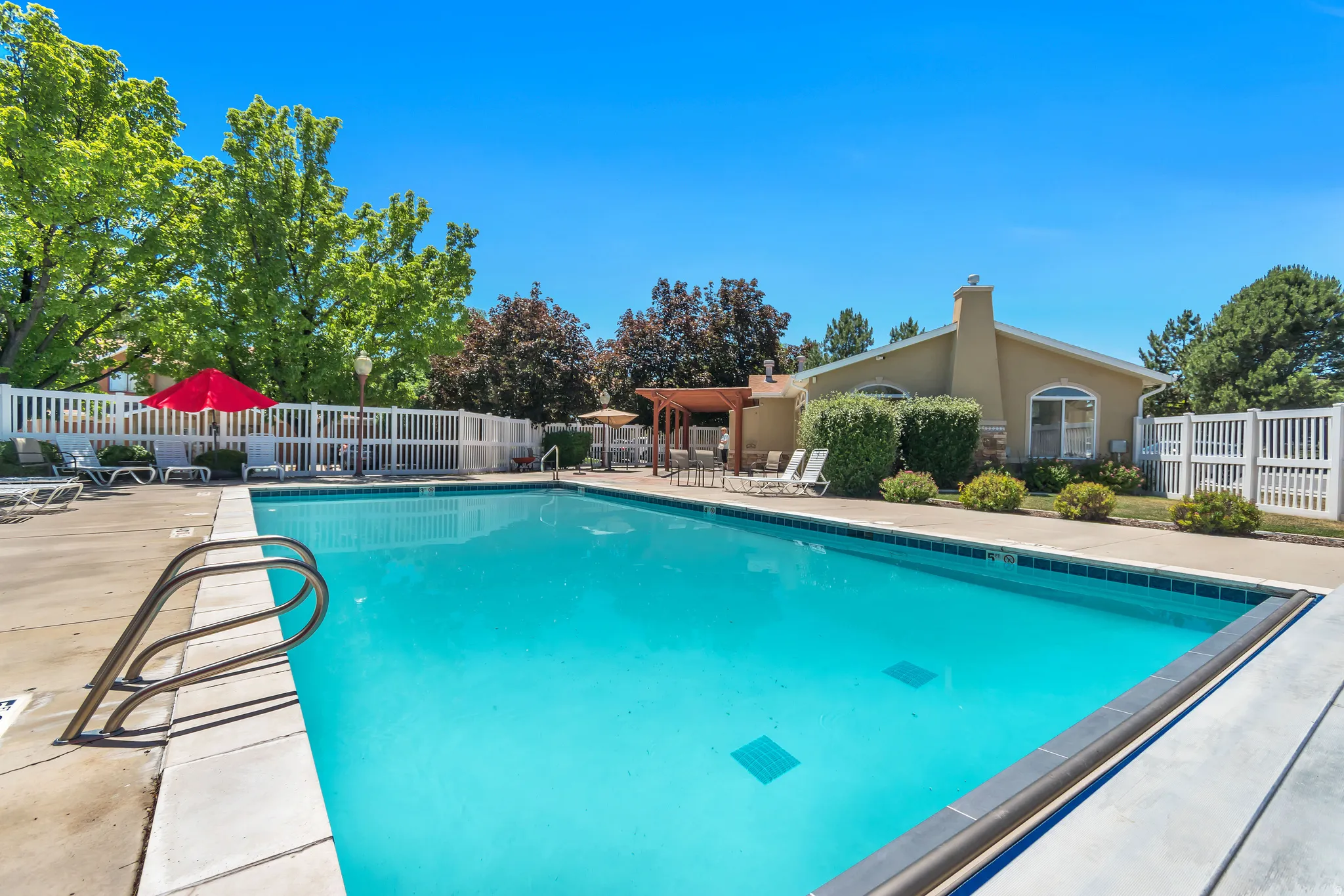 Outdoor swimming pool featuring a concrete deck and metal entry rails