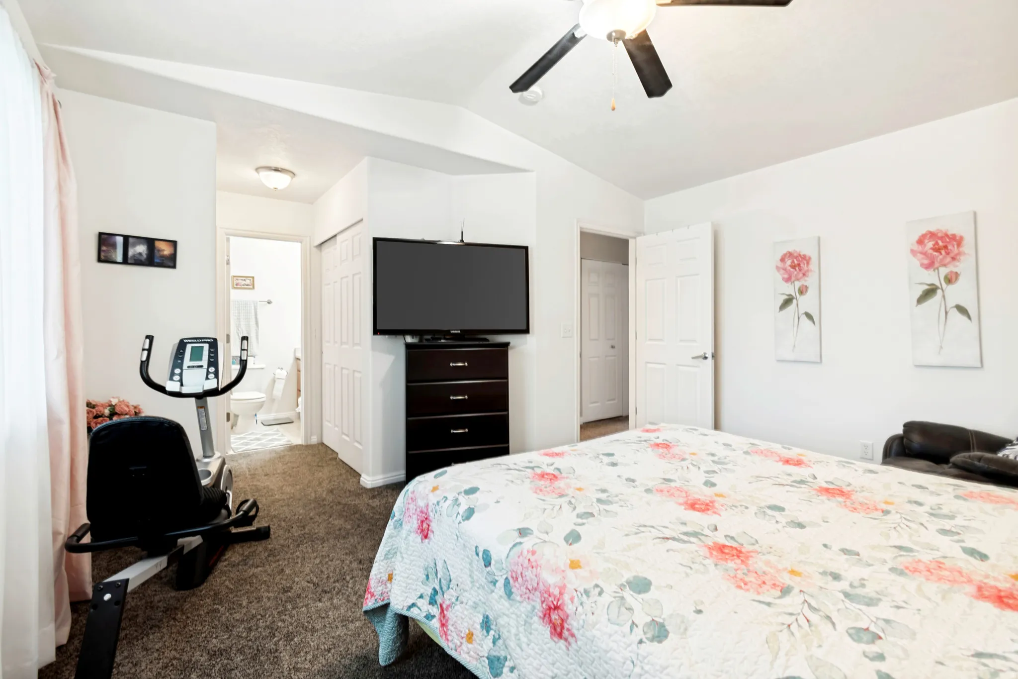 Carpeted bedroom featuring white walls and a ceiling fan with integrated lighting