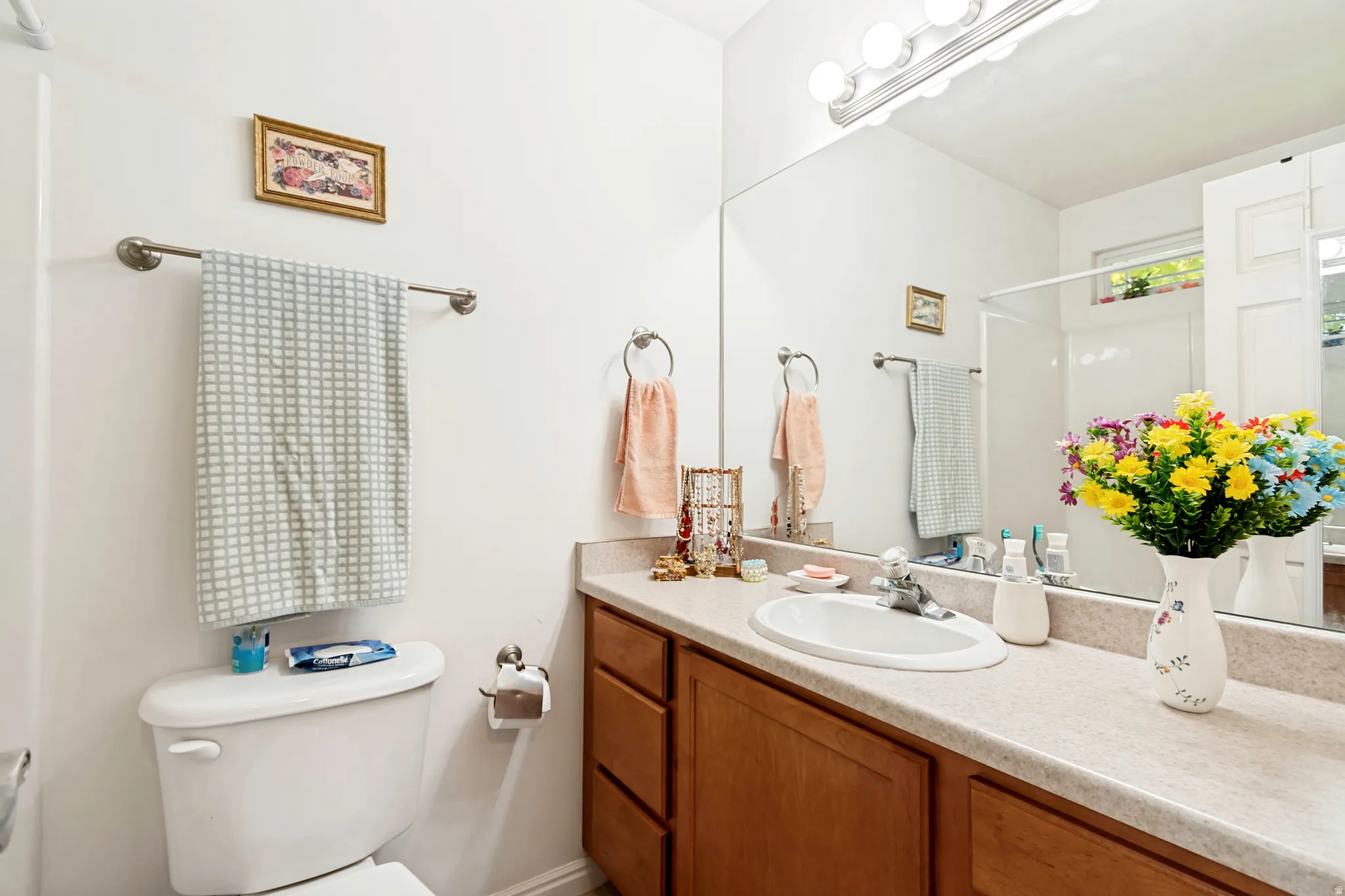 Bathroom vanity with wood-finish cabinetry, a light-toned countertop, and an integrated oval sink