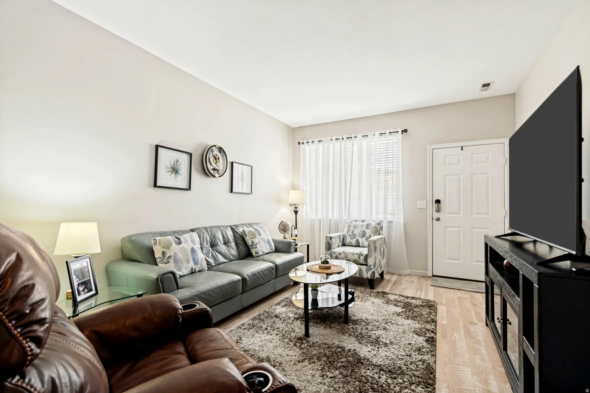 Open living area featuring wood-finish flooring, a neutral color palette, and a white paneled entry door