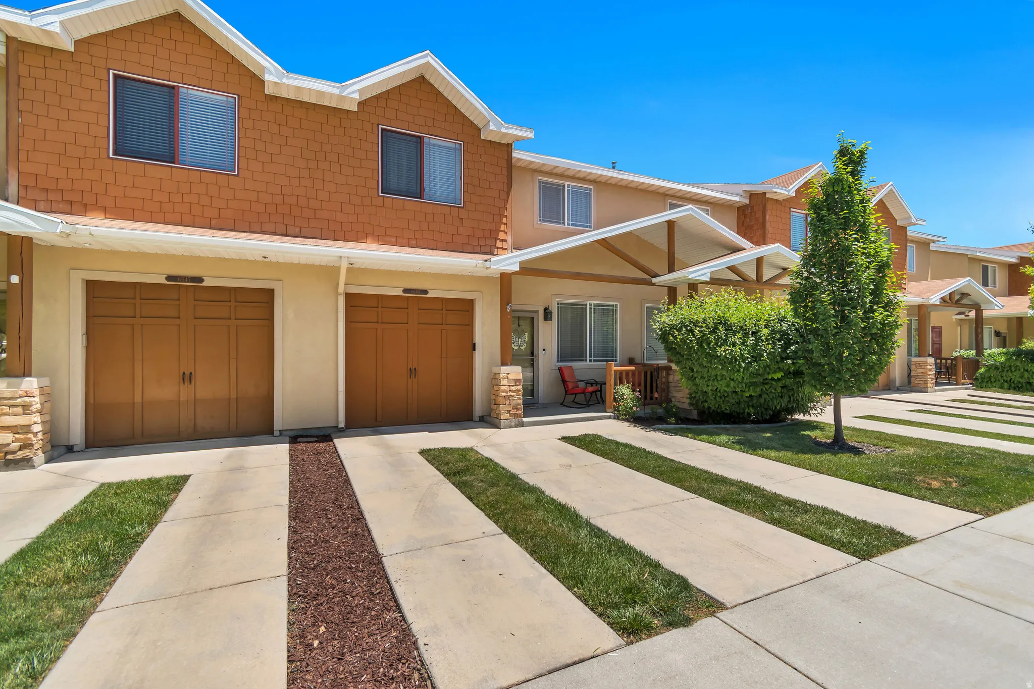 Townhome exterior featuring tan stucco and horizontal brown siding