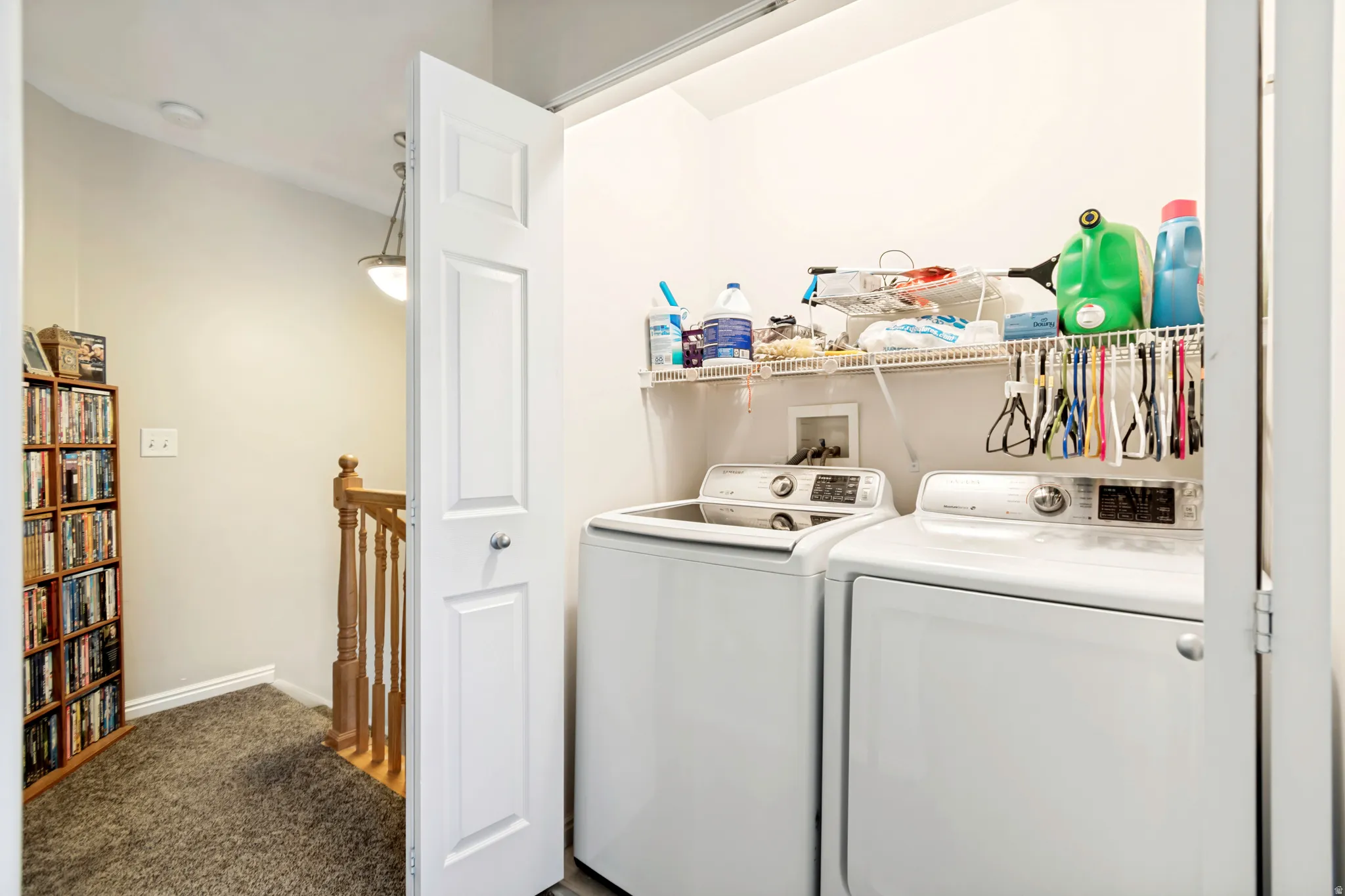 Dedicated laundry area featuring a white washing machine, white clothes dryer, and wall-mounted wire shelving