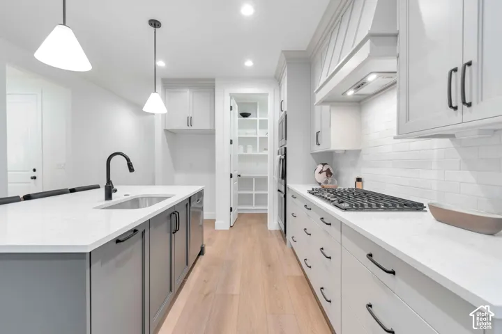 Kitchen featuring quartz countertops, shaker-style cabinetry, a gas cooktop, wood-finish flooring, and a walk-in pantry