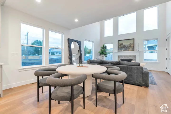 High-ceilinged room with wood-finish flooring, floor-to-ceiling windows, and a built-in fireplace with a stone-tile surround