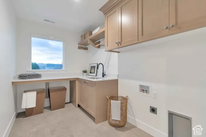 Laundry room featuring light-tone cabinetry, quartz countertops, a drop-in sink with a matte black faucet, open shelving with a hanging rod, and large-format tile flooring